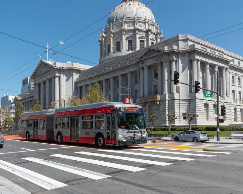 A 49 Van Ness-Mission bus heads down a dedicated transit lane past San Francisco City Hall.