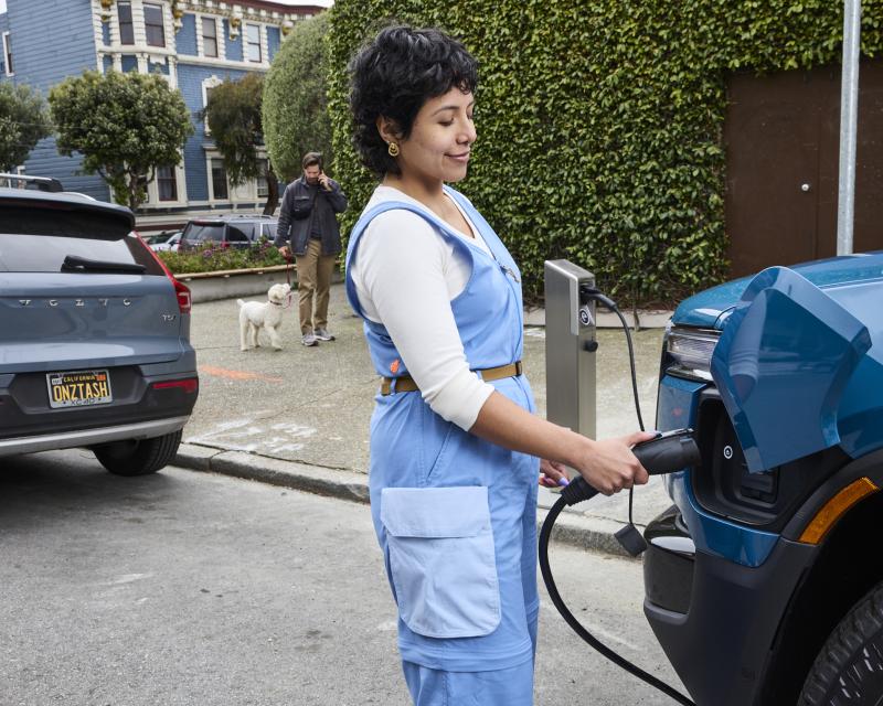 Person charging an electric vehicle at one of the two new curbside EV charging stations in Duboce Triangle.