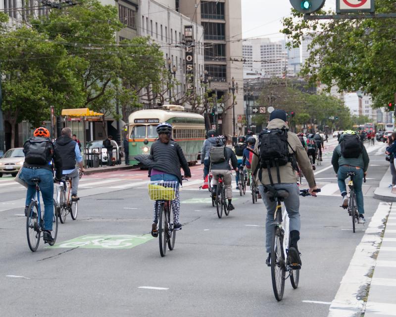 Several people bike on Market Street near F Market historic streetcars.