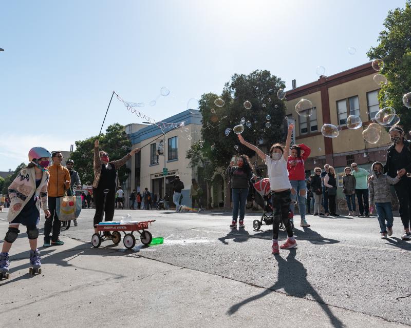 Children and families riding bikes and playing games on a car-free city street.