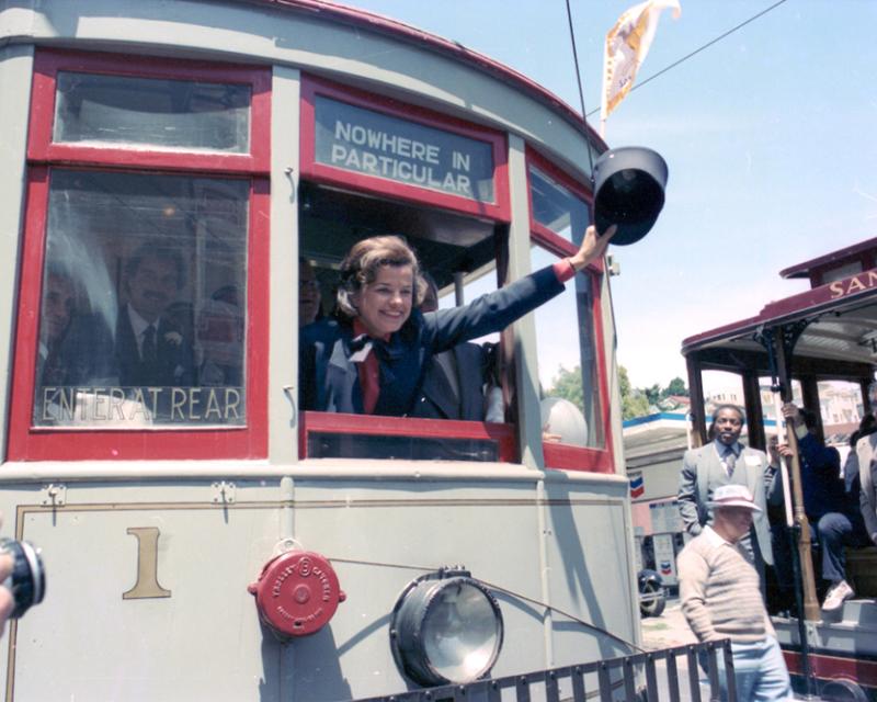 Former San Francisco Mayor Dianne Feinstein waves a Motorman's hat out the front window of Muni Car 1.