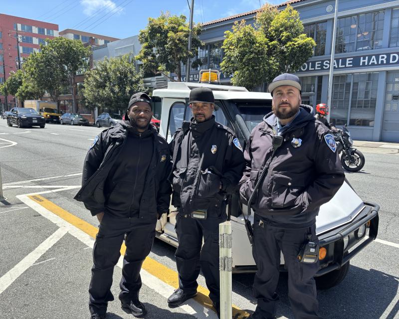 Three men standing in front of a small white vehicle.
