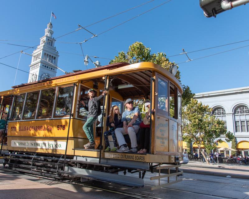 People riding a vintage vehicle during Muni Heritage Weekend.