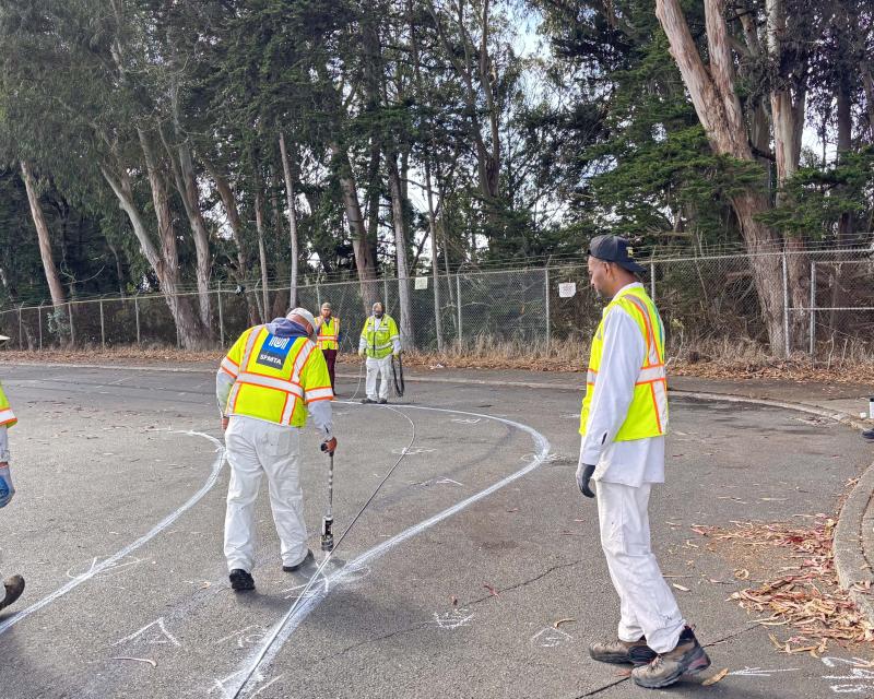 SFMTA workers lay out new bike lanes within the parking lot at Sloat Blvd and Skyline Blvd.