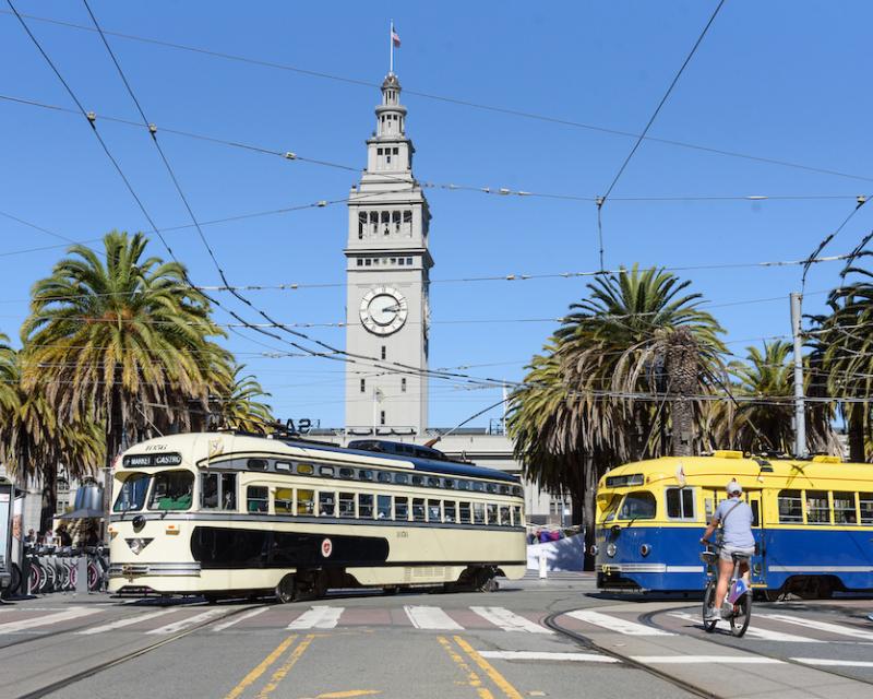 Two F Market streetcars turn left on the Steuart Street curve toward Market Street.