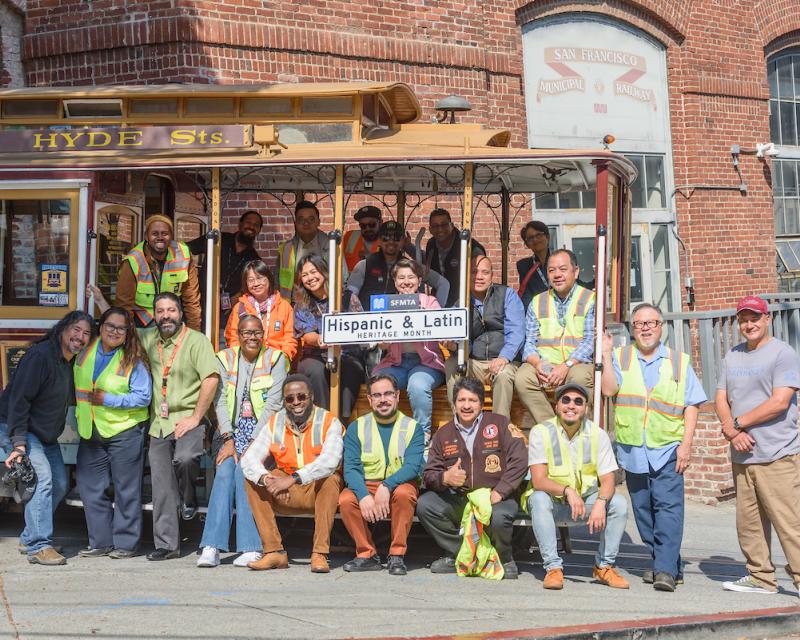 People sitting on a cable car in front of a building.