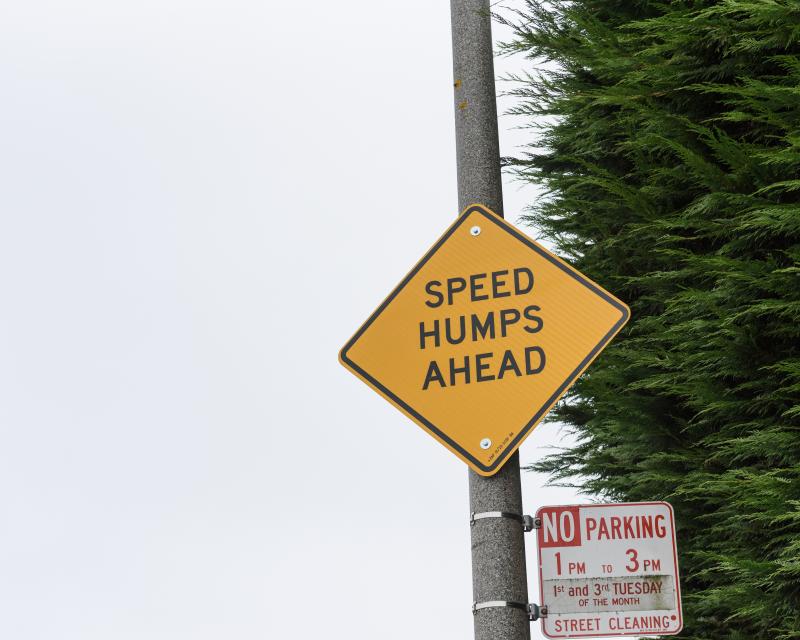 Yellow sign reads "Speed Humps Ahead"