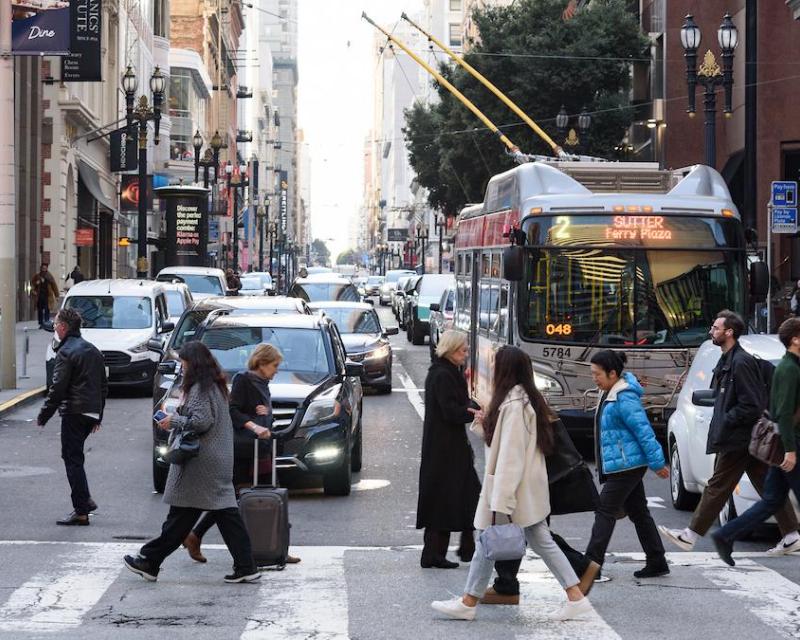 people walking across a street in front of a bus