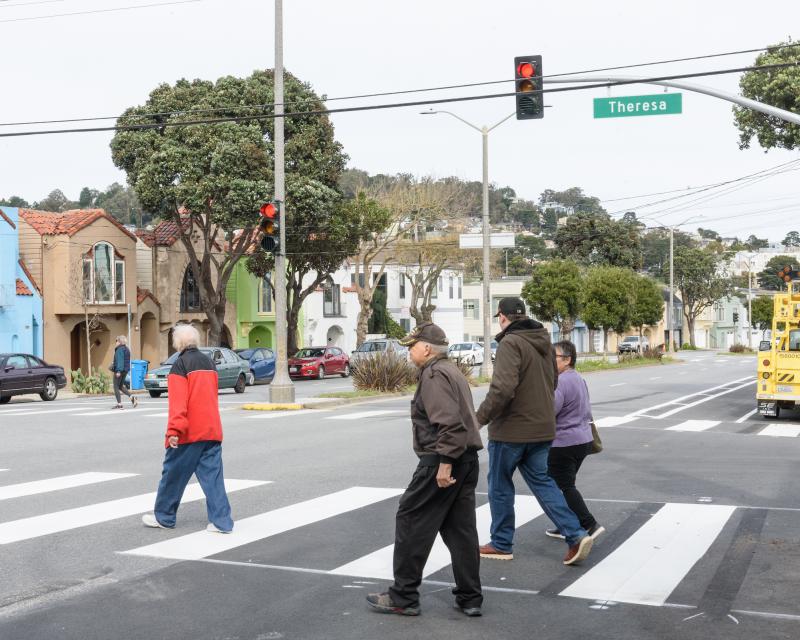 People cross a street at a stoplight. 