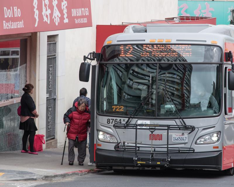 A person using a cane and boarding the 12 Fulton bus.