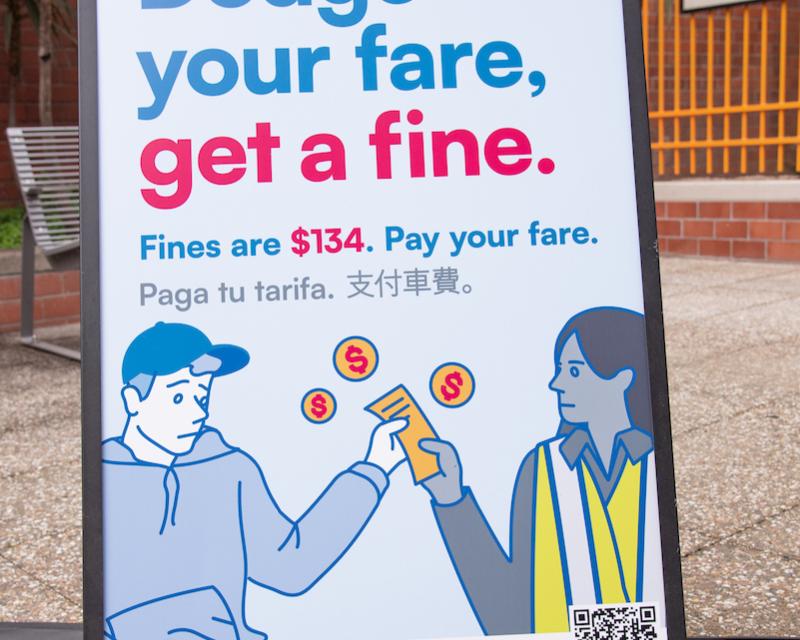 image of a sign that reads "Dodge your fare, get a fine. Fines are $134. Pay your fare," accompanied by an illustration of a person being issued a ticket for non-payment of a transit fare. 