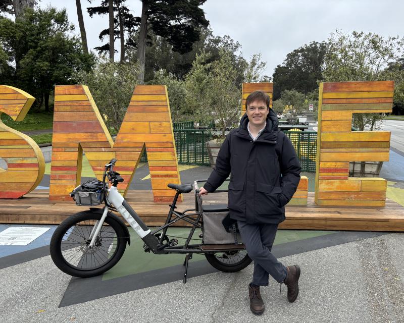 A person with a bike in front of large letters made of wood. 
