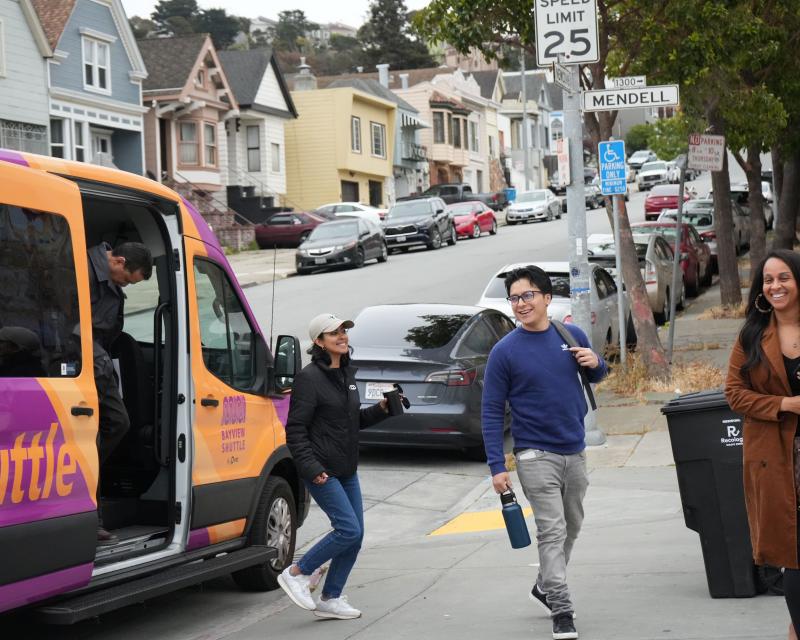 People getting out of a van at the curb.
