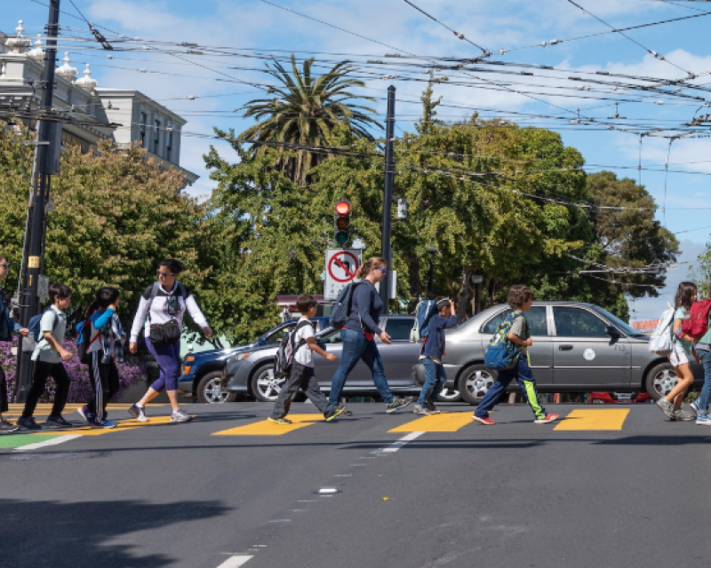Children and adults crossing the street at a crosswalk.