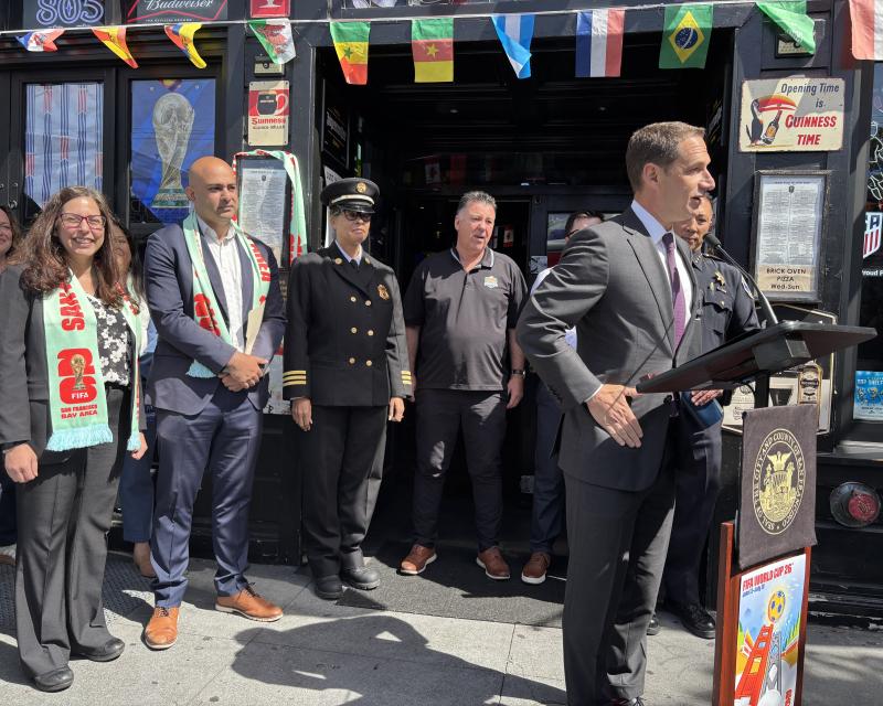 One person standing at a podium with several people behind him.  