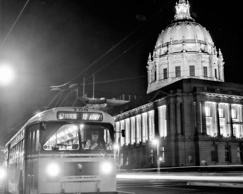 A bus on a street in front of a large civic building