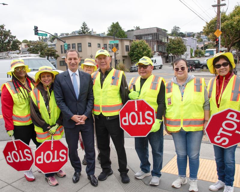 Crossing guards smile for a photo with Mayor Daniel Lurie.