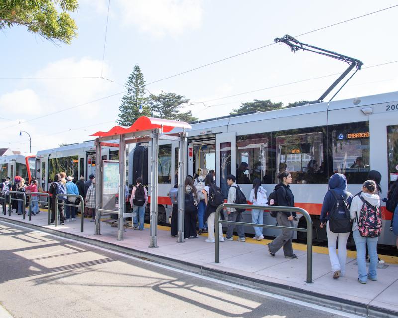 People standing and walking near a transit train at a stop