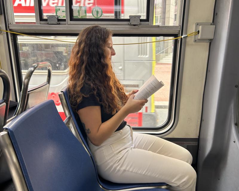 A woman reading while sitting on a bus.