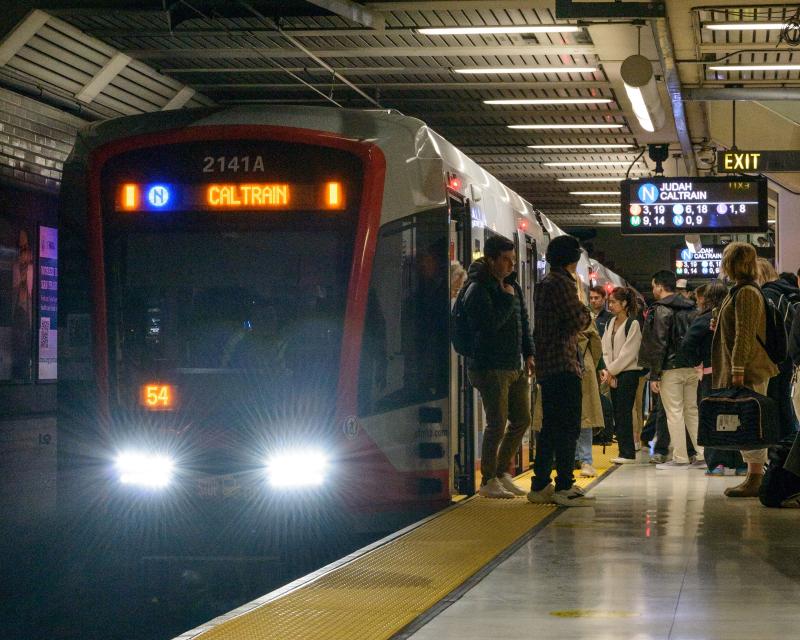 People board a public transit train in a station.