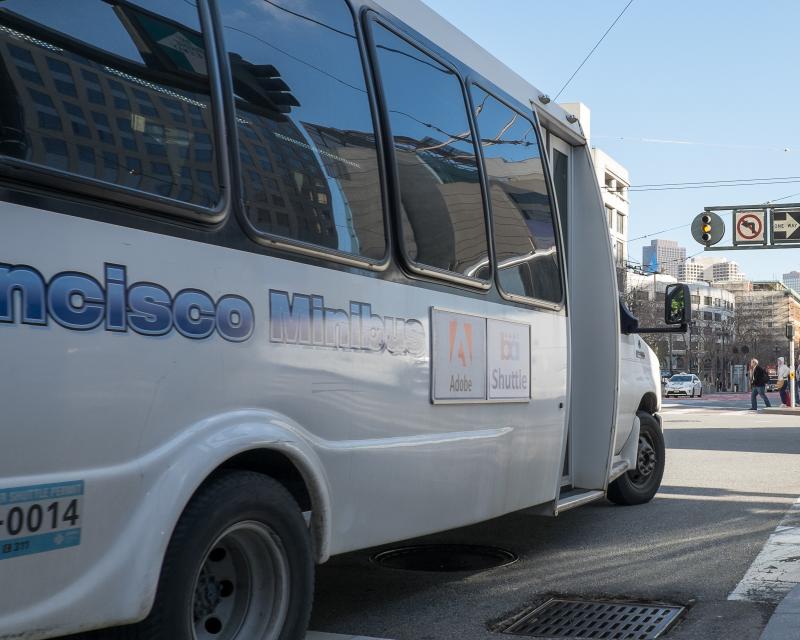 white shuttle van turning corner on Market street