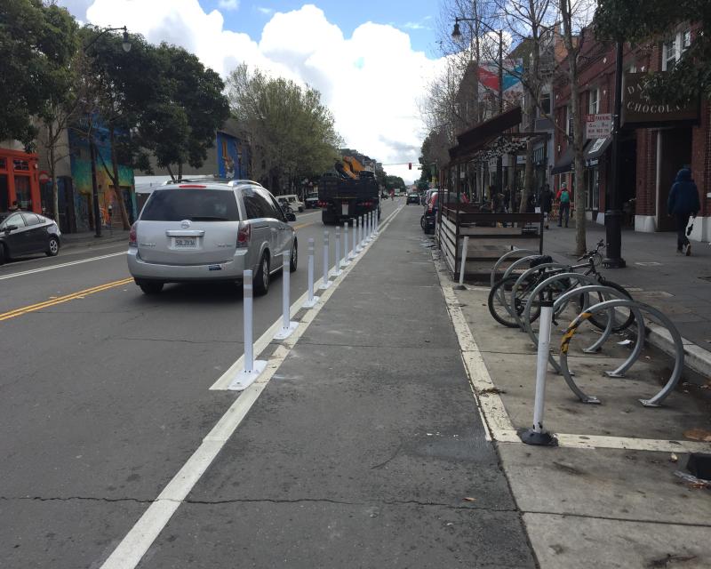 New paint and flext post on Valencia Street in front of a parklet and bike corral