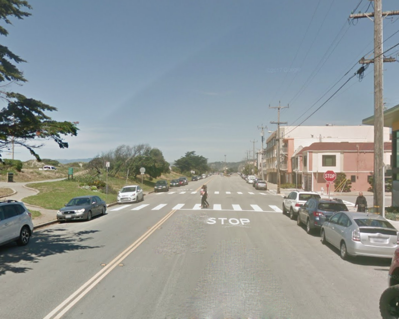 Lower Great Highway approaching Lawton Street, looking north. A pedestrian is crossing in the crosswalk.