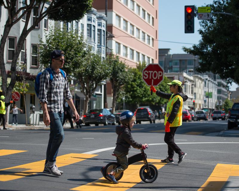 A crossing guard helping a family cross the road.