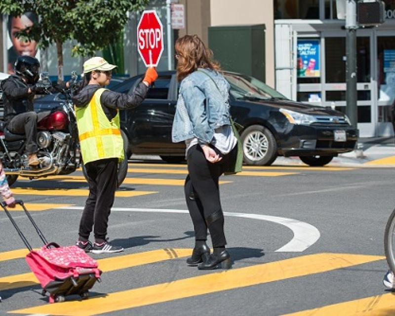 People crossing the street with the help of a crossing guard.