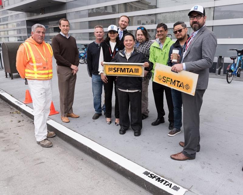 SFMTA staff painting new logo on curbs.