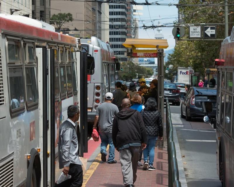 People boarding buses downtown.