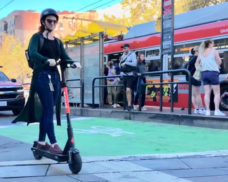 Lady on a e scooter crossing Van Ness