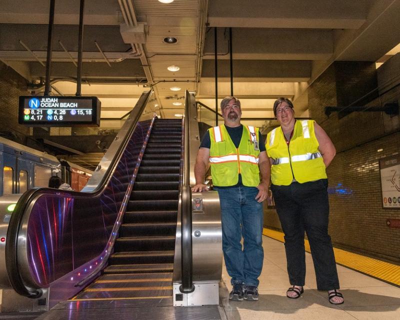 SFMTA staff standing in front of the escalator at Van Ness Station 