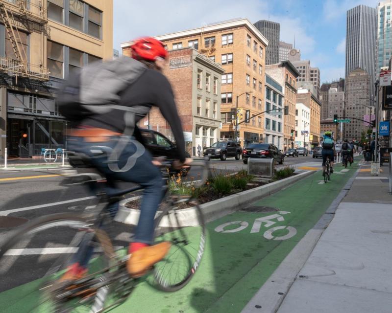 A bicyclist uses the protected bike lane on 2nd Street.