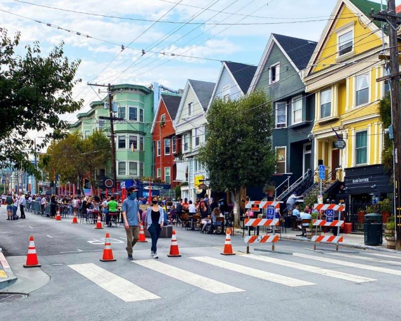 The 18th Street Shared Space with people eating and walking with traffic cones to prevent cars.
