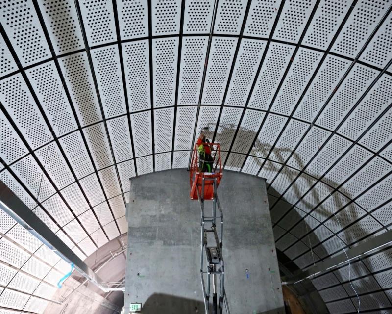 A worker installs decorative panels in a future Central Subway Station.