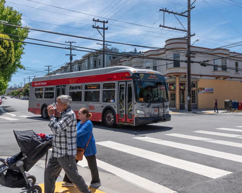 27 Bryant and two people crossing with a stroller on Bryant Street at 20th St in the Mission  