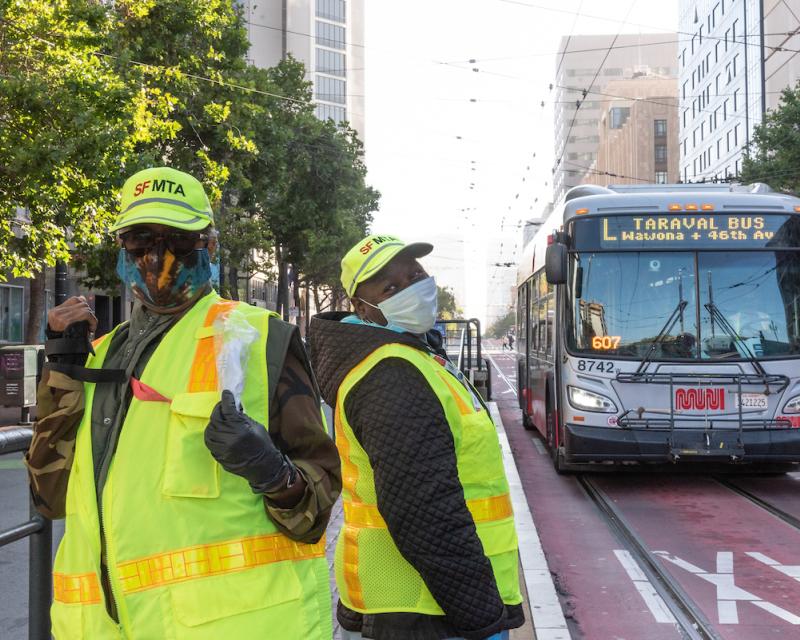 Two Muni Ambassador pose in front of a bus.