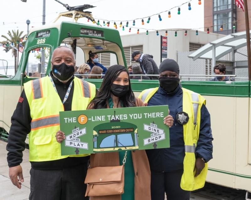 Photo of SFMTA staff holding "The F Line Takes You There" sign