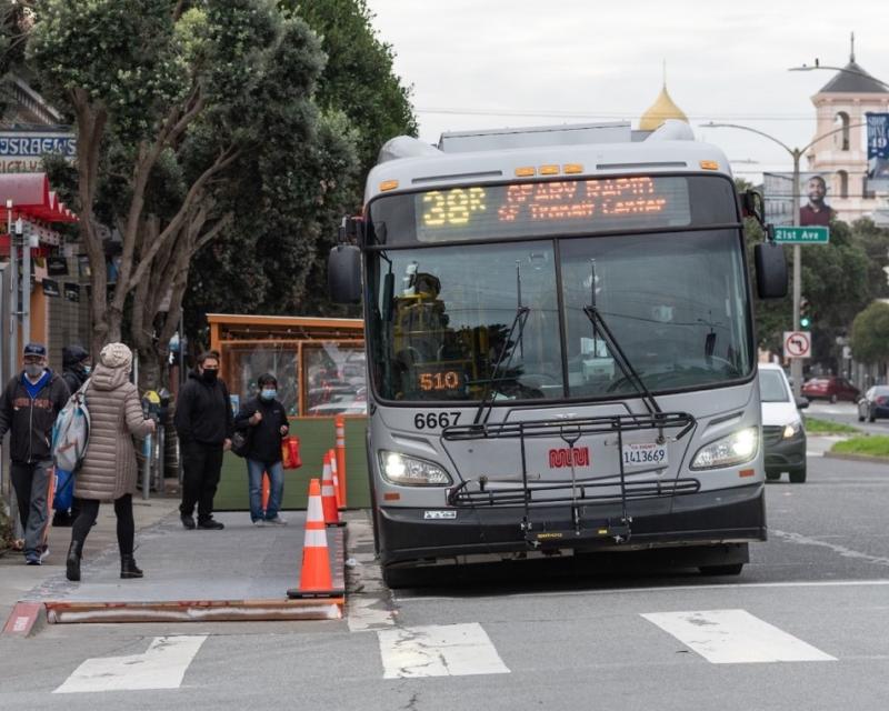 Passengers board a 38R Geary Rapid in the Richmond District with the help of a temporary wooden "bus bulb."