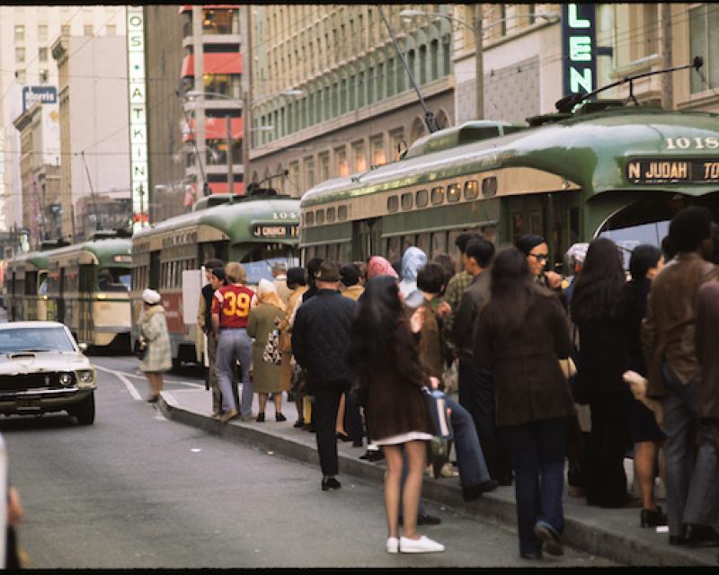 Muni platform overflowing with people waiting for streetcars as people board