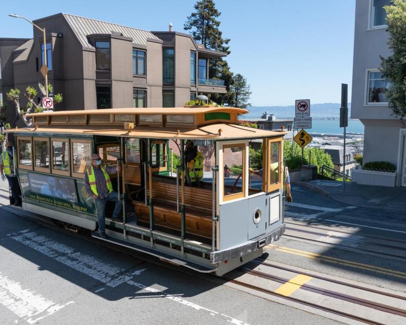 Photo of Powell Hyde cable car with three staff members wearing masks