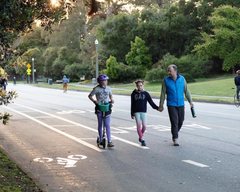 a family walking and scooting on car-free JFK Drive