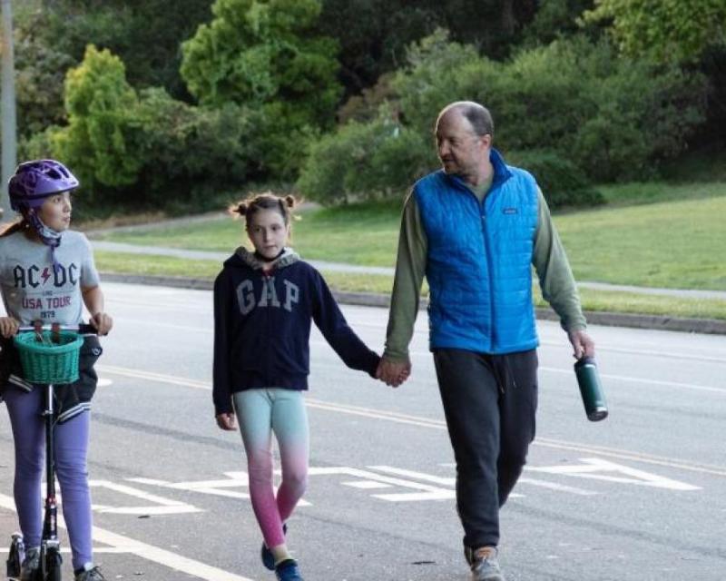 Photo of man holding child's hand while they walk in Golden Gate Park