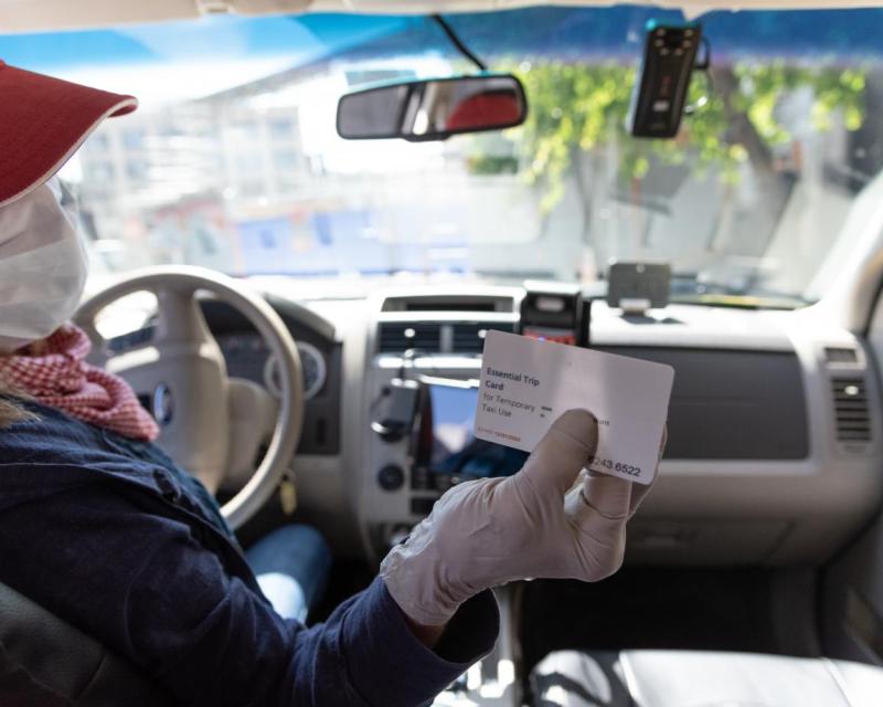 Image of taxi driver holding essential trip card