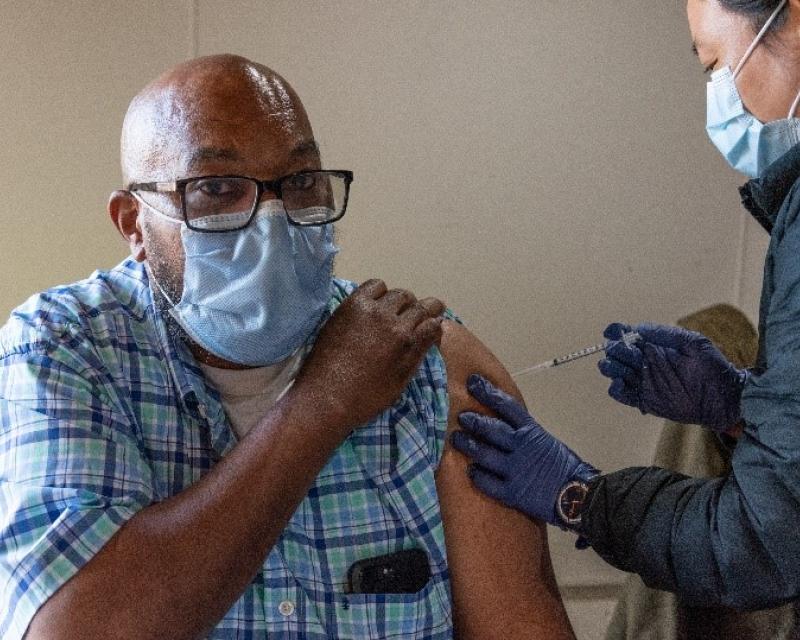 Photo shows a man receiving a vaccination.