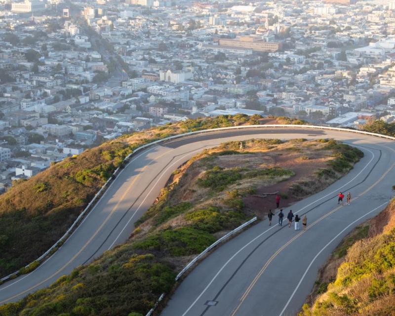 People walking up to Twin Peaks with the city skyline in the background