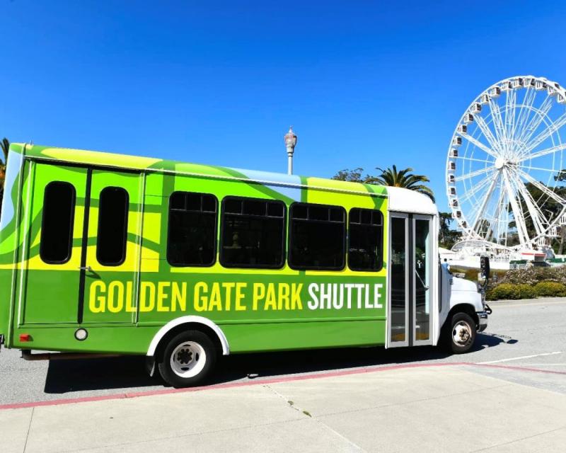 The Golden Gate Park shuttle is shown with the ferris wheel in the background. The sky is bright blue and cloudless