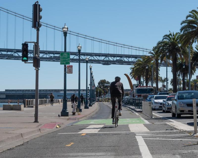 Biking along the Embarcadero in the designated bike lanes overlooking the Bay Bridge and waterfront view 