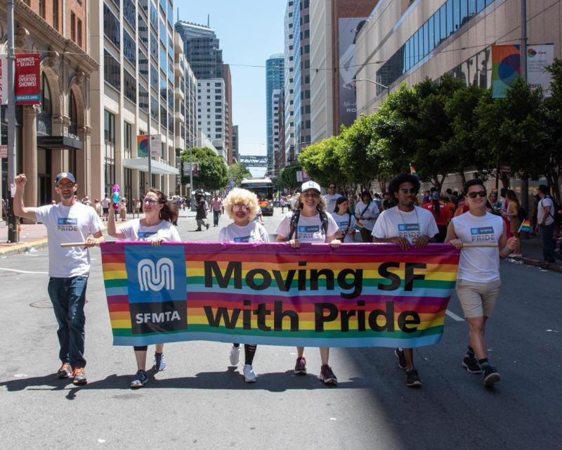 MTA participants holding a banner displaying "Moving SF with Pride" in the Pride Parade on city streets 